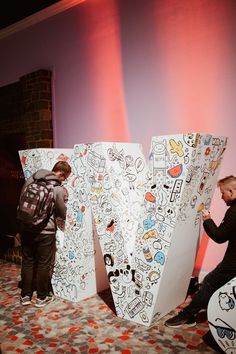 two people with backpacks standing next to large letters