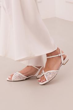 Step into the spotlight with our Kore wedding flat sandals, the epitome of luxury and elegance. These stunning white bridal flats feature a flattering butterfly-shaped toe strap, handcrafted from supple leather and structured mesh, adorned with exquisite hand-embroidered lace. Tiny transparent sequins and blue beads lend a subtle sparkle, offering a perfect "something blue" for your big day. Designed for both style and comfort, the Kore white bridal flats are richly padded to cushion every step, Bridal Shoes Flats Sandals, White Wedding Shoes Flats, Bridal Sandal, Something Blue For Bride, Flat Sandals Wedding, Bridal Flats, Wedding Shoes Flats, Bridal Sandals, Wedding Flats