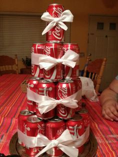 a stack of coca cola cans with white ribbons on them, stacked in the shape of a christmas tree