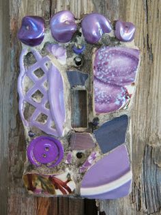 a piece of art made out of glass and buttons on a wooden fence post,