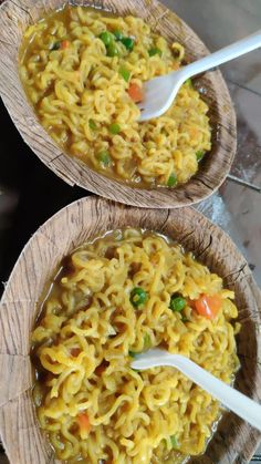 two wooden bowls filled with noodles and vegetables