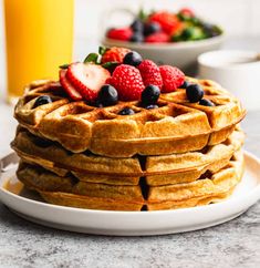 a stack of waffles with strawberries and blueberries on top