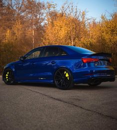 a blue car is parked on the side of the road in front of some trees