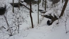 a man walking up a snow covered path in the woods