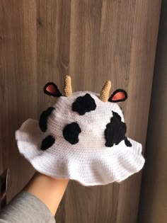 a hand is holding a knitted cow hat