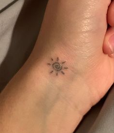 a small sun tattoo on the foot of a woman's left foot, which is black and white