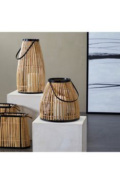 three bamboo baskets sitting on top of each other in front of a wall with a painting behind them