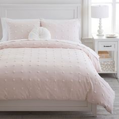 a white bed with pink comforter and pillows