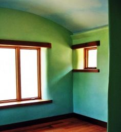 an empty room with green walls and wooden floors