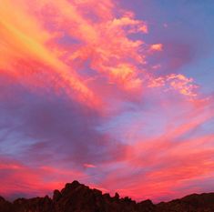 the sky is pink and blue as it sets in the distance with rocks on either side