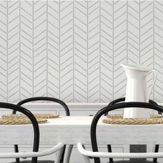 two chairs and a table in front of a wall with white chevron tiles on it