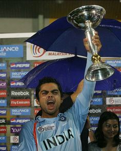 a man holding up a trophy and an umbrella