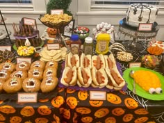 a table topped with lots of hot dogs on buns covered in toppings and candy