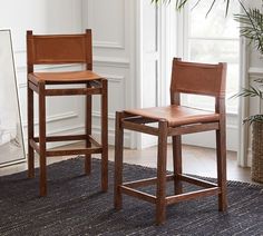 two wooden barstools sitting on top of a rug in front of a window