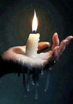 a person holding a candle in their hand with water dripping from the top and bottom