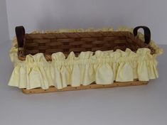 a basket with ruffles on the bottom and handles is sitting on a table