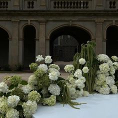 white flowers and greenery are on display in front of an old building with arches