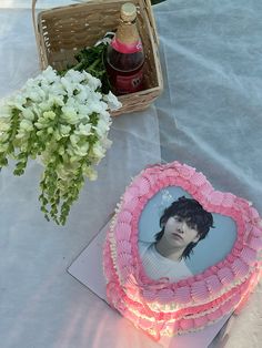 there is a cake with a picture on it next to flowers and a basket full of bottles