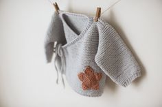 a knitted sweater hanging on a clothesline with an orange heart attached to it