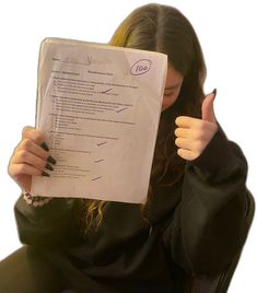 a woman sitting in a chair holding up a piece of paper with writing on it