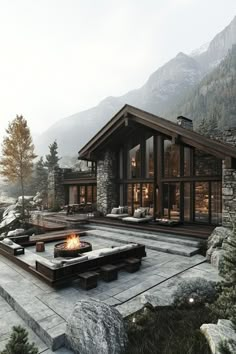 an outdoor fire pit in the middle of a stone patio surrounded by trees and mountains