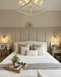 a white bed sitting under a light fixture in a bedroom