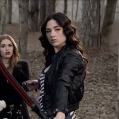 two women in the woods holding swords and looking at each other with serious expressions on their faces