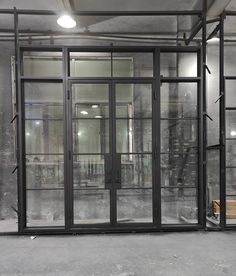 an empty room with glass doors and metal pipes on the wall, in front of a window