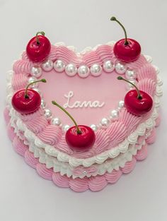 a heart - shaped cake with cherries and pearls on the edges that spell love