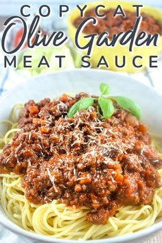 a white bowl filled with spaghetti and meat sauce on top of a blue table cloth