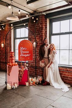 Bride in three quarter length puff sheer sleeve wedding dress with delicate polka dot overlay and square neck posing with groom in brown blazer, white shirt, grey suit trousers and vans shoes next to retro wedding decor | Stephanie Butt Photography Colourful Retro Wedding, Quirky Wedding Ideas Unique, Retro Wedding Theme Decor, Retro Country Wedding, Disco Wedding Backdrop, Retro Wedding Colors, Kitsch Wedding Decor, Quirky Wedding Decor, 70s Wedding Theme