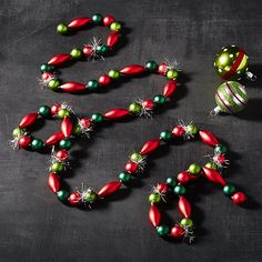 christmas ornaments are arranged on a black surface with green and red balls in the middle