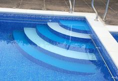 an empty swimming pool with steps leading up to the water's edge and tile flooring