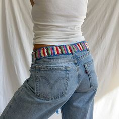 a woman in jeans with a colorful belt around her waist