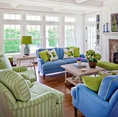 a living room filled with blue couches and green pillows on top of each other