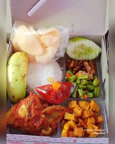 an open box filled with different types of vegetables and meats next to rice, cucumbers, and pickles