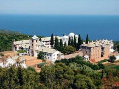 an aerial view of a large building with trees in front of it and the ocean in the background