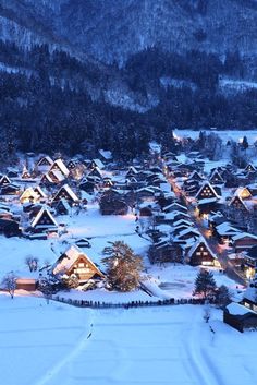 an aerial view of a village in the mountains at night with snow on the ground