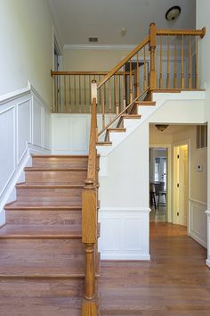 a wooden stair case in a home with white walls and wood floors, along with hardwood flooring