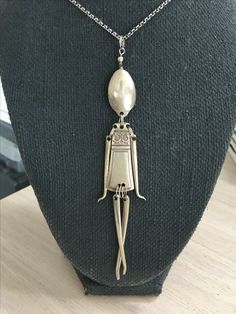 a silver necklace with a white pearl hanging from it's center