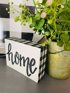 a potted plant sitting next to a sign that says home on the side of a table