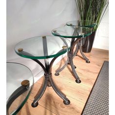 three glass tables sitting on top of a wooden floor next to a potted plant