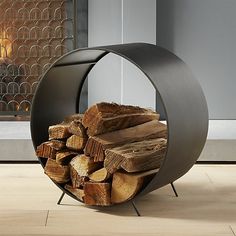 a stack of logs sitting inside of a round metal container on top of a wooden floor