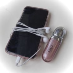 an electronic device with earbuds connected to it on a white table next to a cell phone