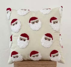 a pillow with santa claus on it sitting on a wooden stool in front of a white wall