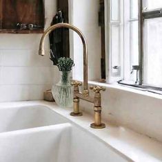 a white sink sitting under a window next to a faucet in a bathroom