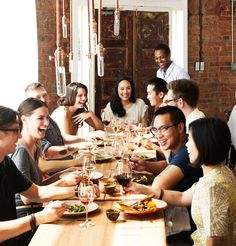 a group of people sitting at a table with food and drinks in front of them