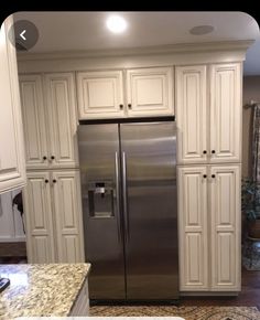 a stainless steel refrigerator in a kitchen with white cabinets and granite counter tops on the island