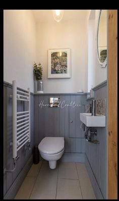 a white toilet sitting in a bathroom next to a wall mounted radiator and sink