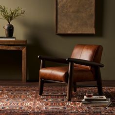 a brown leather chair sitting on top of a wooden floor next to a table with a potted plant